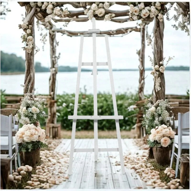 Un chevalet en bois se tient au centre d'une allée de mariage en plein air, entouré de chaises en bois, de fleurs et d'une arche rustique décorée, offrant une vue sur un paysage pittoresque.